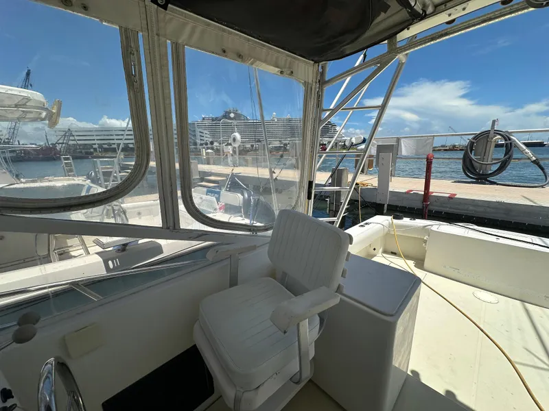 Slide: The Image of 2003 Carolina Classic 28 boat interior at dock, featuring seating and clear windows. - 16