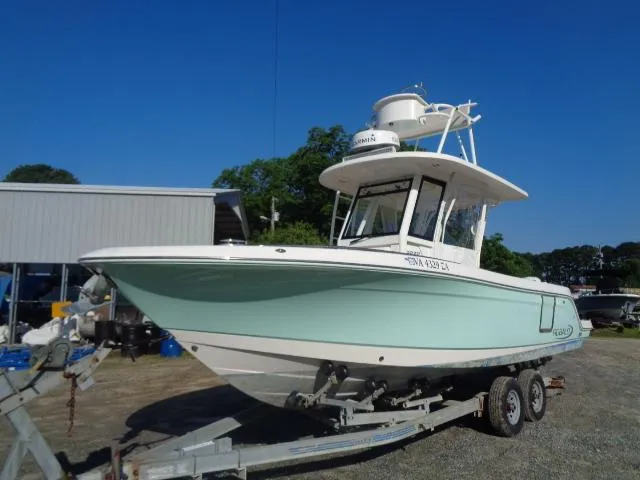 Slide: The Image of 2019 Robalo R272 Center Console boat on trailer, parked outdoors under clear blue sky. - 2