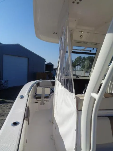 Slide: The Image of 2019 Robalo R272 Center Console boat with protective cover, docked near a storage building. - 27