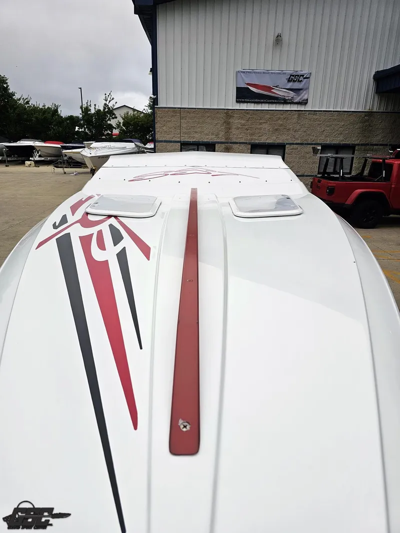 Slide: The Image of 2005 Baja 25 Outlaw boat with red and black graphics, parked outside a building. - 16