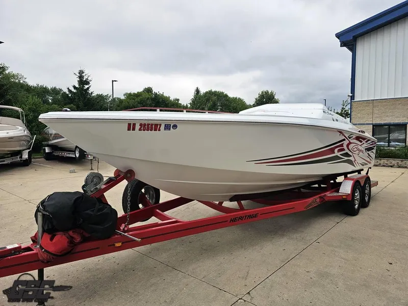 Slide: The Image of 2005 Baja 25 Outlaw boat on red trailer, parked outdoors near building. - 19