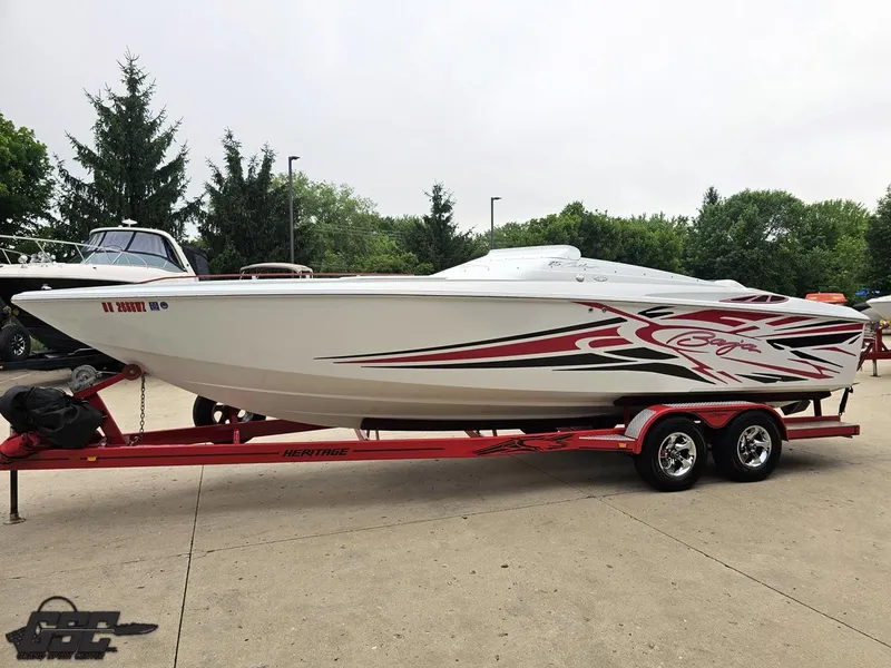 Slide: The Image of 2005 Baja 25 Outlaw boat on red trailer, parked outdoors with trees in background. - 21