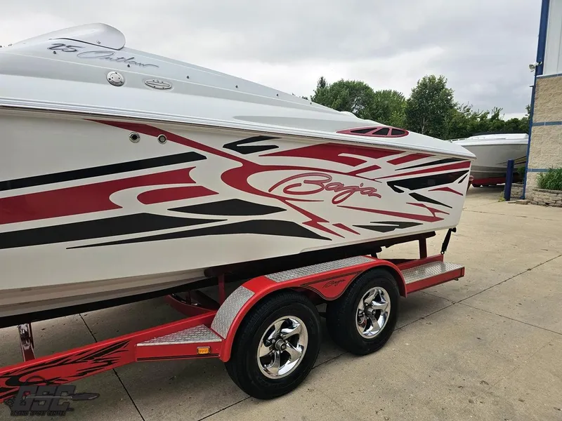 Slide: The Image of 2005 Baja 25 Outlaw boat with red and black graphics on a trailer. - 24