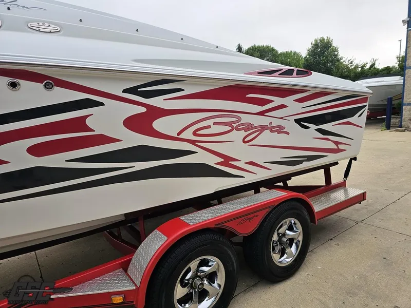 Slide: The Image of 2005 Baja 25 Outlaw boat with red and black graphics on a trailer. - 25