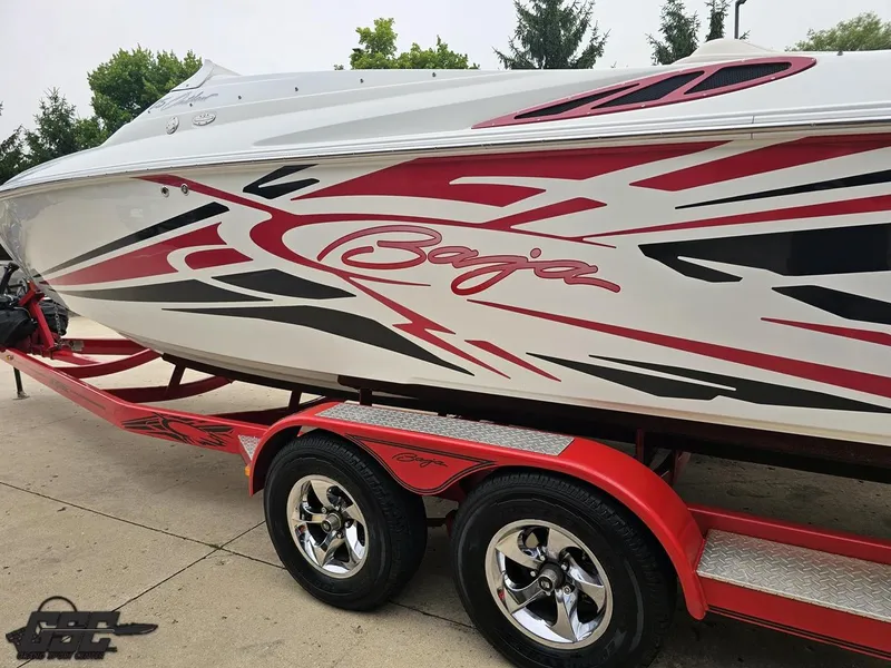Slide: The Image of 2005 Baja 25 Outlaw boat with red and black graphics on a matching trailer. - 30