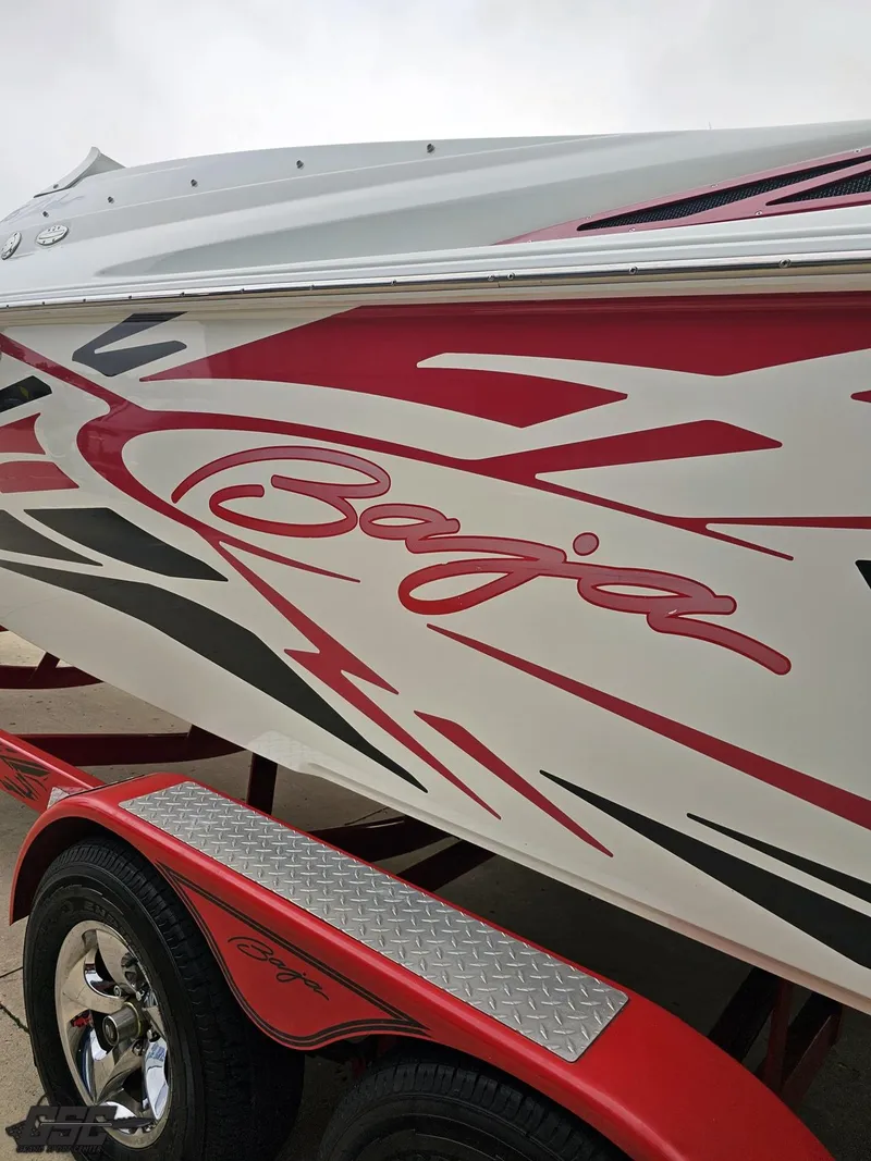 Slide: The Image of 2005 Baja 25 Outlaw boat with red and black graphics on a matching trailer. - 32