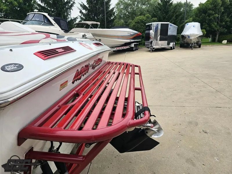 Slide: The Image of 2005 Baja 25 Outlaw boat with red swim platform, parked among other boats and trailers. - 33