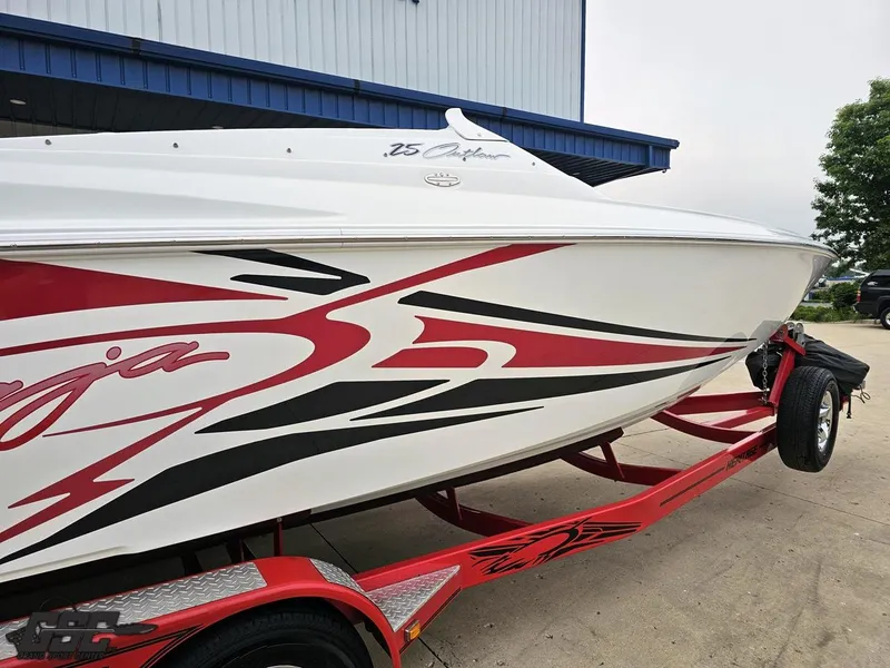 Slide: The Image of 2005 Baja 25 Outlaw boat with red and black graphics on a trailer. - 8