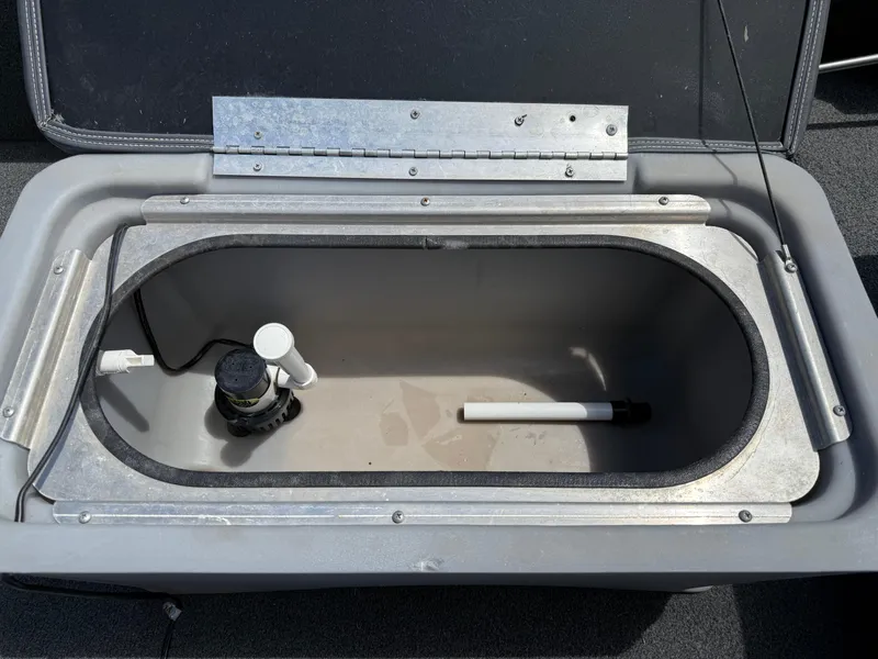 Slide: The Image of Open livewell compartment in a 2018 Lowe Stryker 16 boat, featuring pump and plumbing. - 15