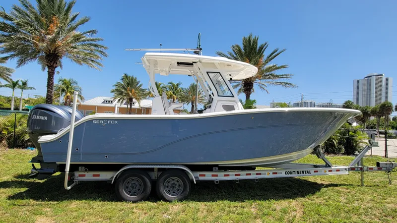 Slide: The Image of 2024 Sea Fox 288 Commander boat on trailer, parked outdoors with palm trees. - 4