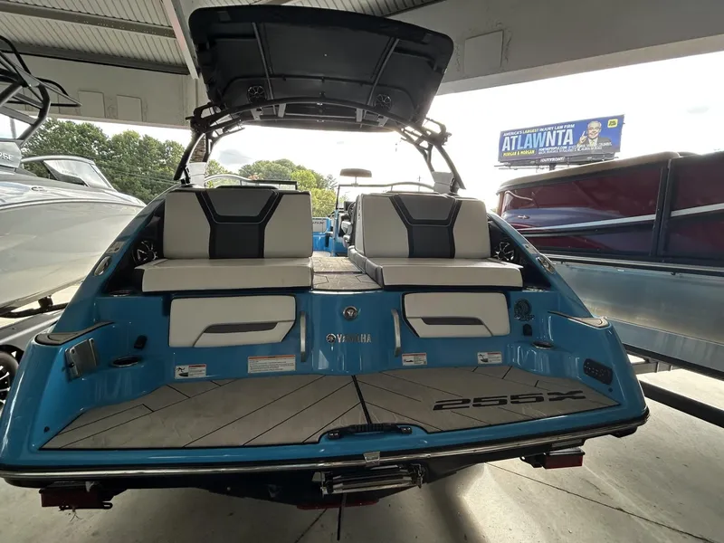 Slide: The Image of 2023 Yamaha Boats 255 XD, rear view, blue exterior, docked under shelter. - 7