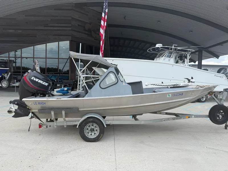 Slide: The Image of Small Hanko 17 boat on trailer, Evinrude motor, parked outside building, American flag visible. - 22