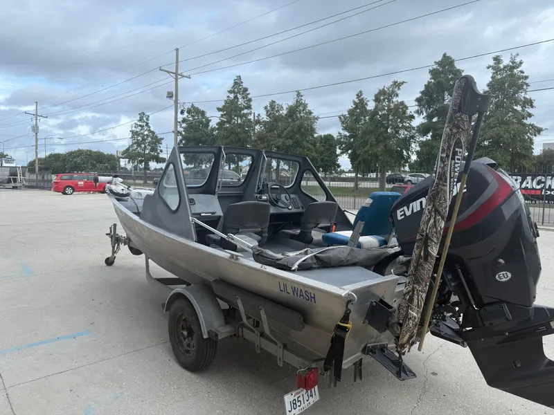 Slide: The Image of Aluminum Hanko 17 boat on trailer with Evinrude outboard motor, parked outdoors, 2015 model. - 9