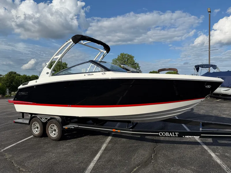 Slide: The Image of 2025 Cobalt R6 boat on trailer, black and white design, parked outdoors under cloudy sky. - 1