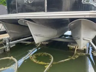 Slide: The Image of 2018 Avalon Catalina 2385QL pontoon boat on water, showing pontoons and dock ropes. - 2