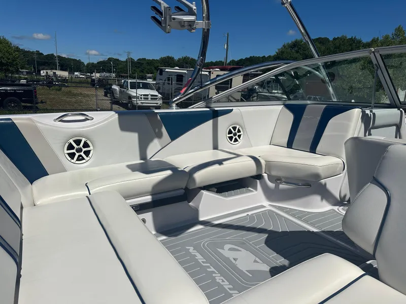 Slide: The Image of 2009 Nautique Super Air 210 boat interior with white and blue seating, outdoor setting. - 11