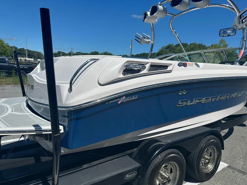 Slide: The Image of 2009 Nautique Super Air 210 boat on trailer, blue and white design, sunny day. - 13