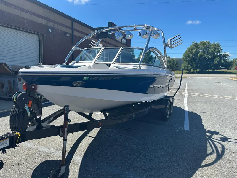 Slide: The Image of 2009 Nautique Super Air 210 boat on trailer, parked outdoors under clear sky. - 3