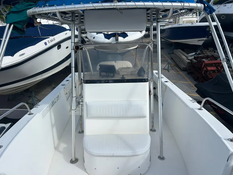 Slide: The Image of 1998 Cobia 224 CC boat interior with seating and console, docked among other boats. - 11