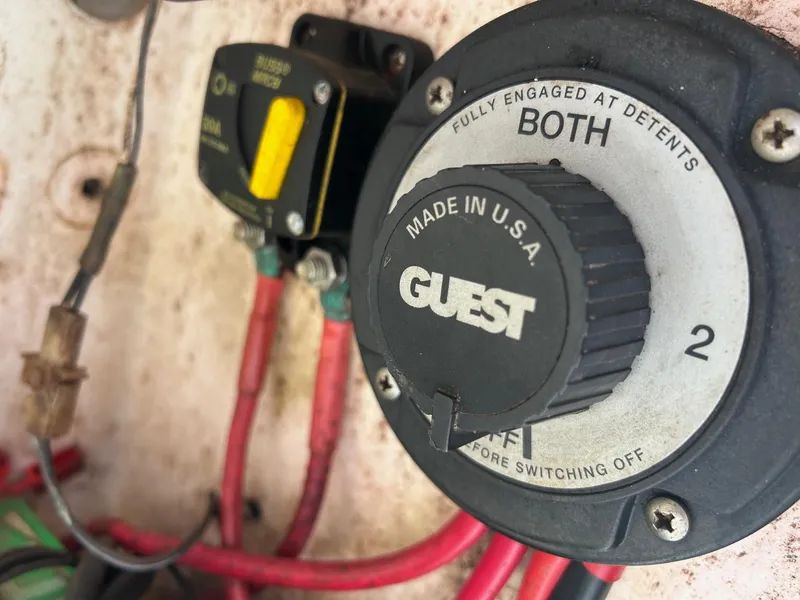 Slide: The Image of Battery switch on a 1998 Cobia 224 CC boat, featuring red cables and "Guest" branding. - 19