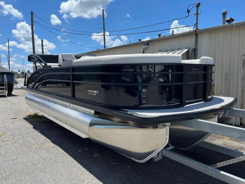 The Image of 2026 Harris Cruiser 210 pontoon boat on trailer, parked outdoors under a blue sky. - 0