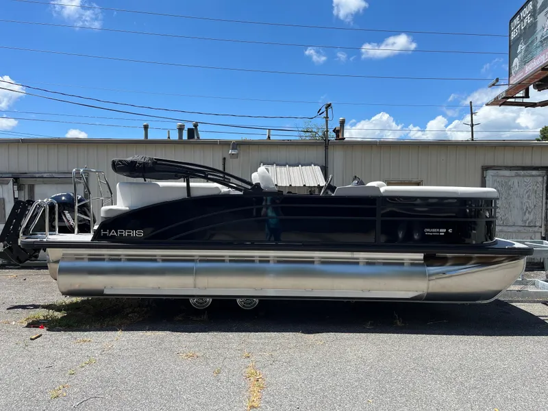 Slide: The Image of 2026 Harris Cruiser 210 pontoon boat on trailer, surrounded by greenery. - 1