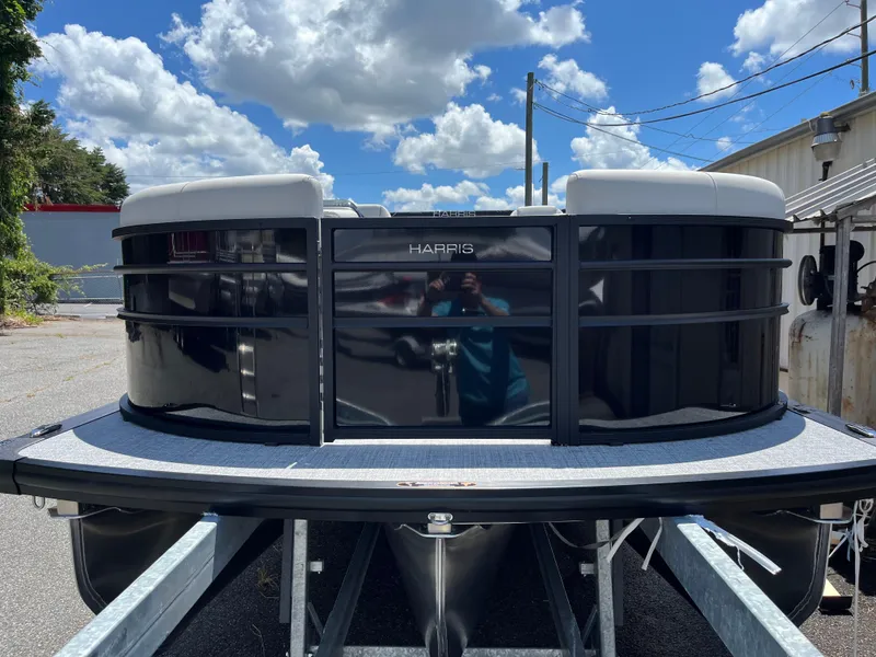 Slide: The Image of 2026 Harris Cruiser 210 pontoon boat parked outdoors under a clear blue sky. - 2