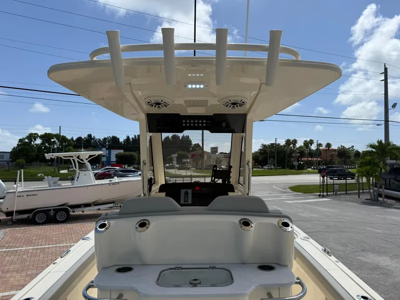 Slide: The Image of 2024 Scout 281 XSS boat interior with rod holders and seating, parked outdoors. - 11