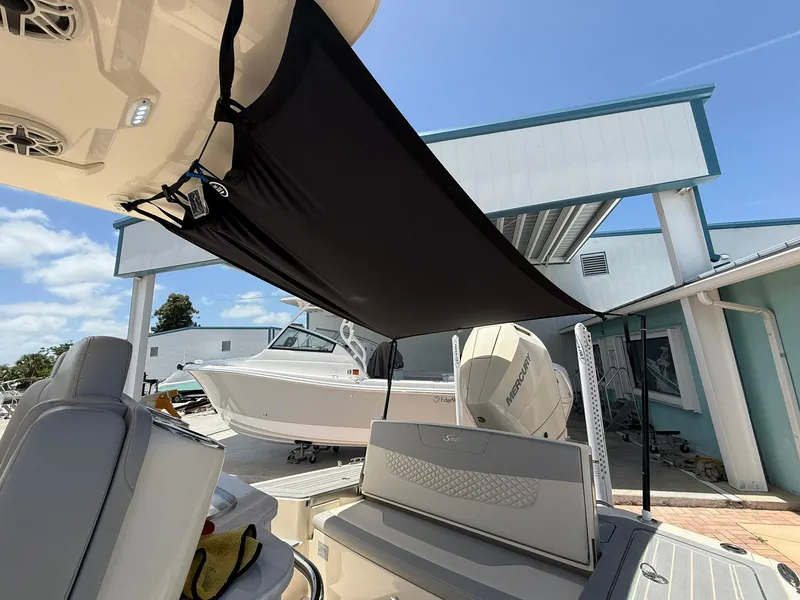 Slide: The Image of 2024 Scout 281 XSS boat with sunshade, docked near a modern building. - 16