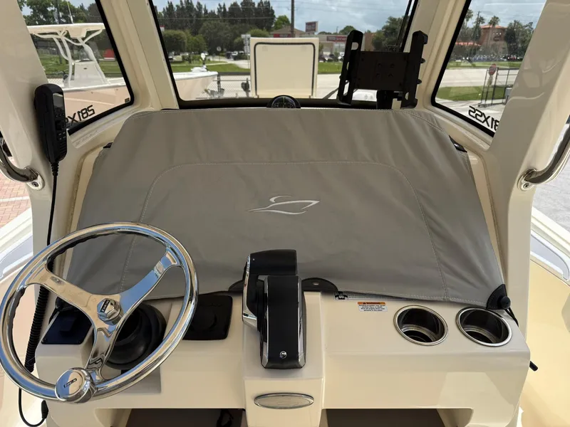 Slide: The Image of 2024 Scout 281 XSS boat dashboard with steering wheel and covered controls. - 23