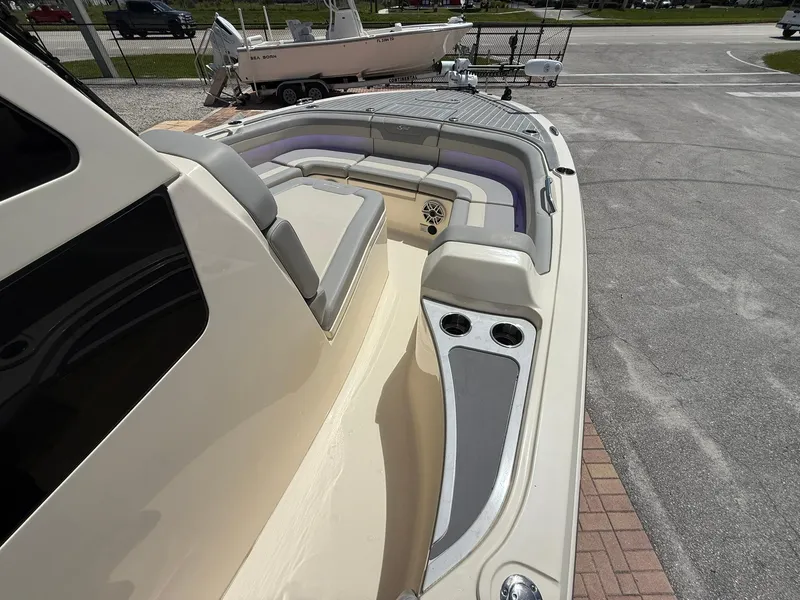 Slide: The Image of 2024 Scout 281 XSS boat interior with seating and cup holders, parked on pavement. - 27