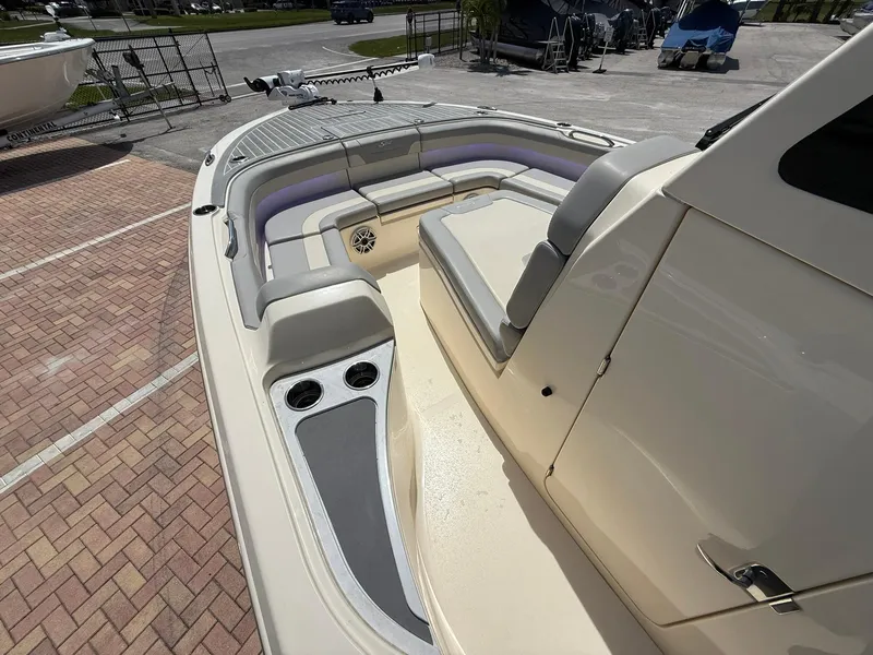 Slide: The Image of 2024 Scout 281 XSS boat interior with seating and cup holders, parked on brick pavement. - 28