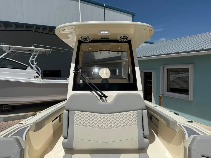 Slide: The Image of 2024 Scout 281 XSS boat interior with modern seating and dashboard, docked near a blue building. - 37