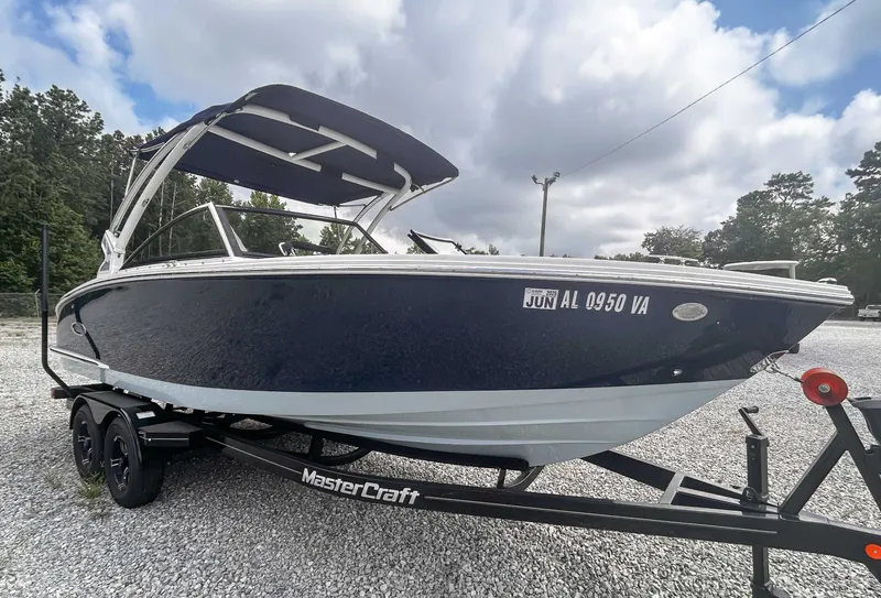 Slide: The Image of 2018 Cobalt CS23 boat on MasterCraft trailer, parked on gravel with trees in background. - 4