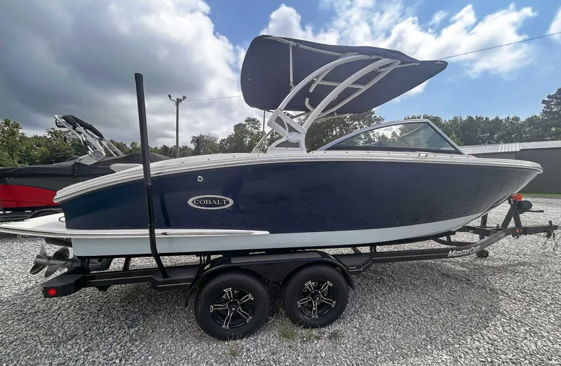 Slide: The Image of 2018 Cobalt CS23 boat on trailer, parked on gravel, under cloudy sky. - 5
