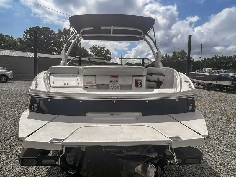 Slide: The Image of 2018 Cobalt CS23 boat, rear view, parked on gravel lot under cloudy sky. - 8