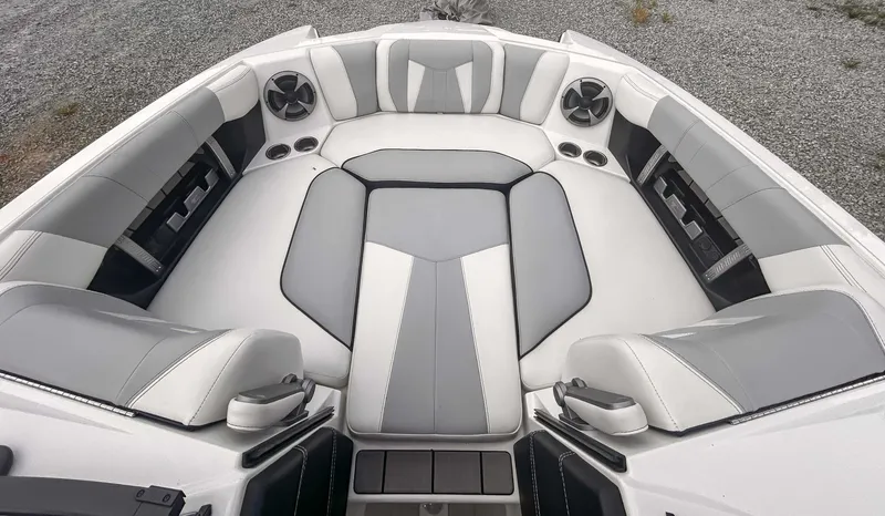 Slide: The Image of 2020 Malibu 23 MXZ boat interior with gray and white seating, speakers, and cup holders. - 11