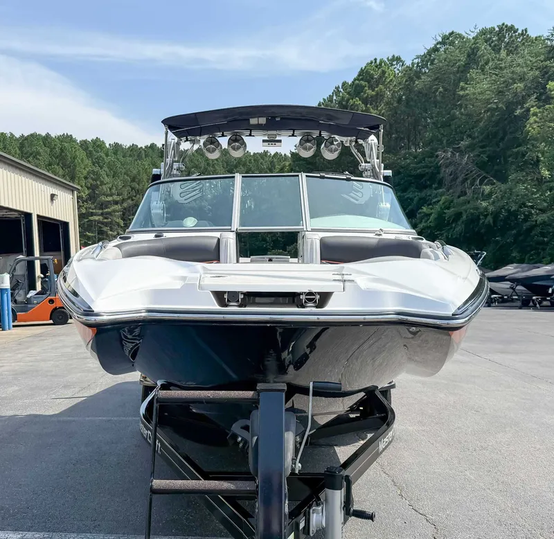 Slide: The Image of 2012 MasterCraft X55 boat on trailer, parked outdoors near trees and buildings. - 4