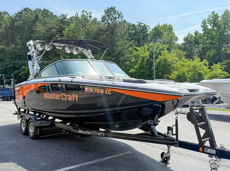 Slide: The Image of 2012 MasterCraft X55 boat on trailer, parked outdoors with trees in background. - 5