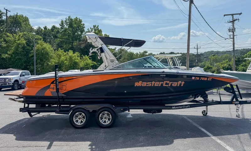 Slide: The Image of 2012 MasterCraft X55 boat on trailer, orange and black design, parked outdoors. - 6