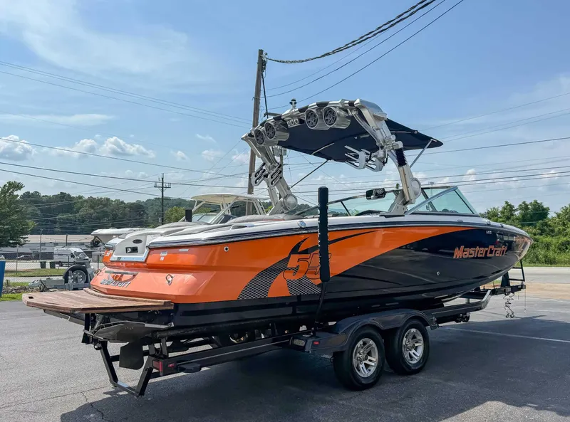 Slide: The Image of 2012 MasterCraft X55 boat on trailer, orange and black design, parked outdoors. - 7