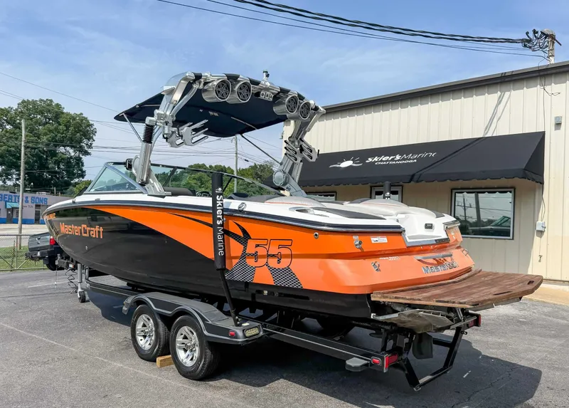 Slide: The Image of 2012 MasterCraft X55 boat on trailer, orange and black design, parked outside Skier's Marine. - 8
