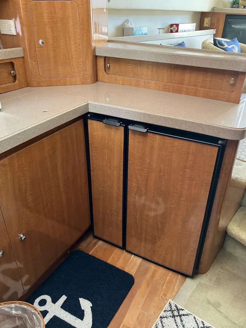 Slide: The Image of 2002 Regal Commodore 3880 yacht interior with wood cabinetry and compact refrigerator. - 11