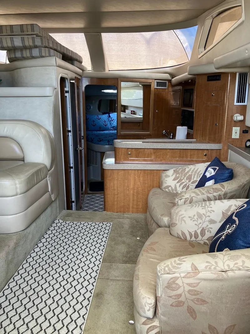 Slide: The Image of Interior of a 2002 Regal Commodore 3880 yacht, featuring plush seating and a compact kitchen area. - 16