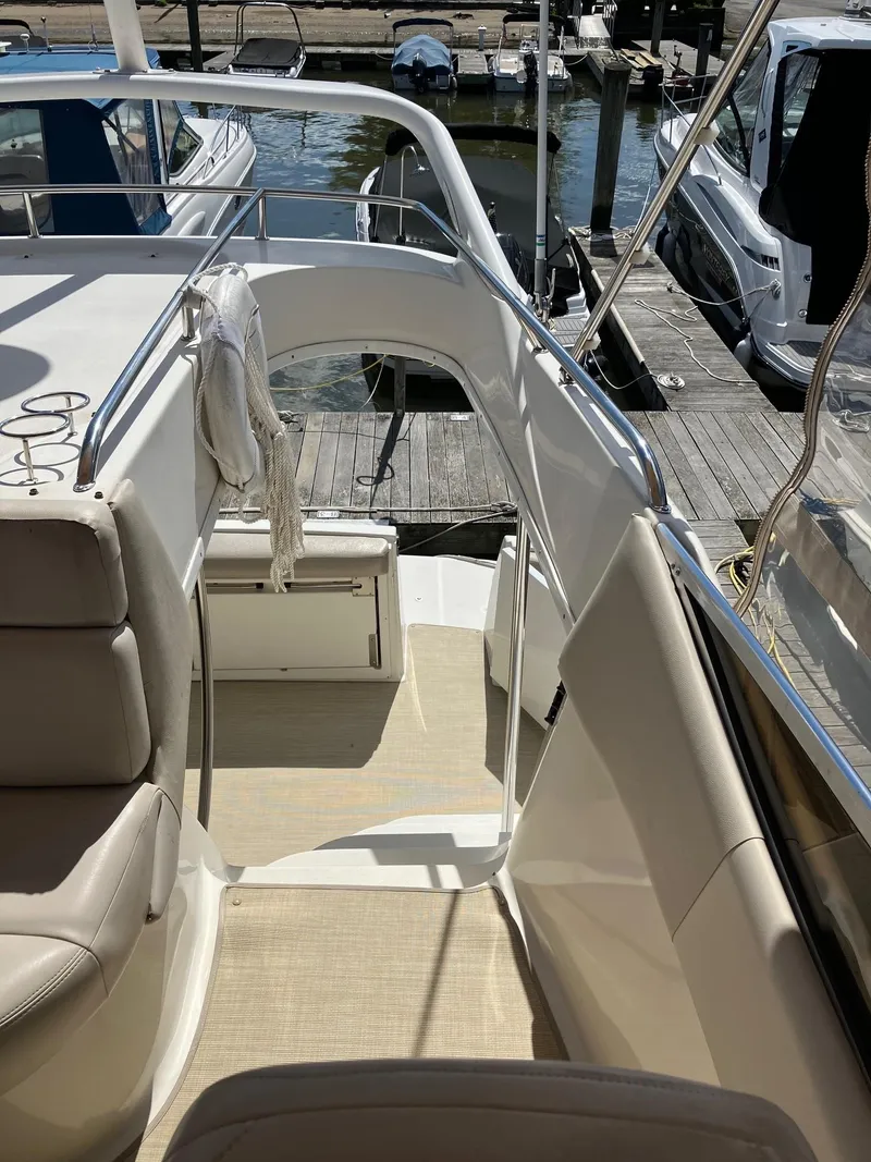 Slide: The Image of 2002 Regal Commodore 3880 yacht interior with beige seating and dock view. - 2