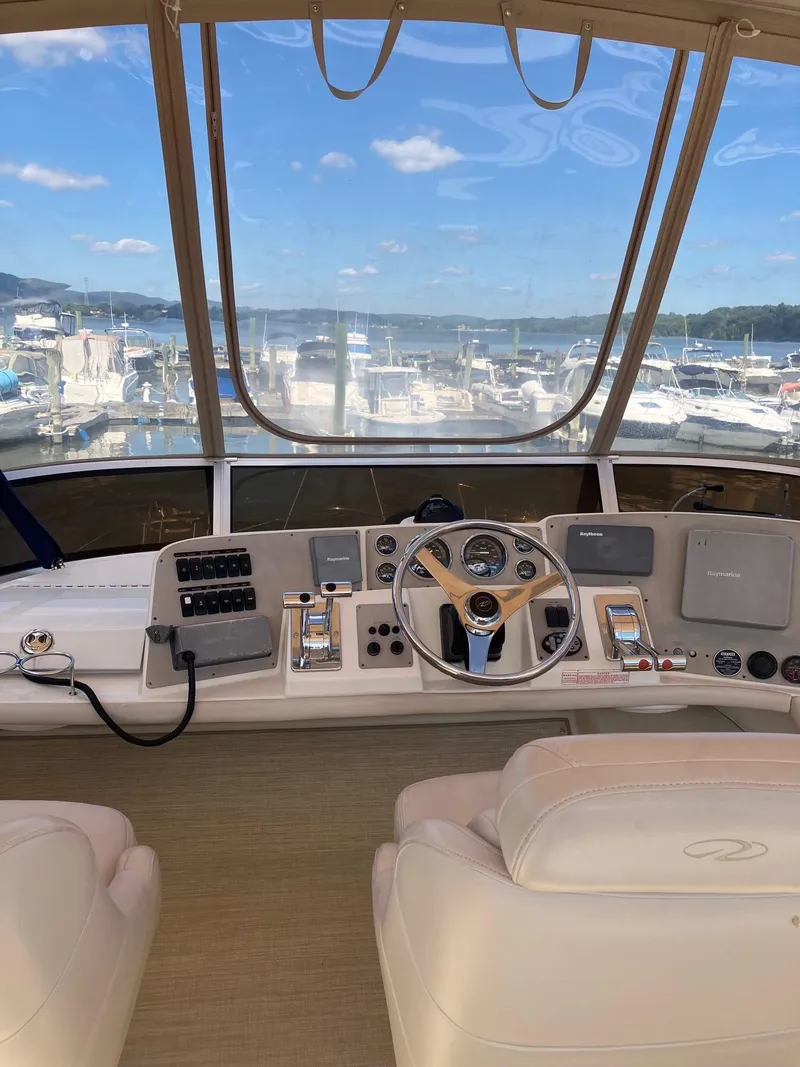 Slide: The Image of 2002 Regal Commodore 3880 yacht helm with marina view, featuring modern controls and comfortable seating. - 8