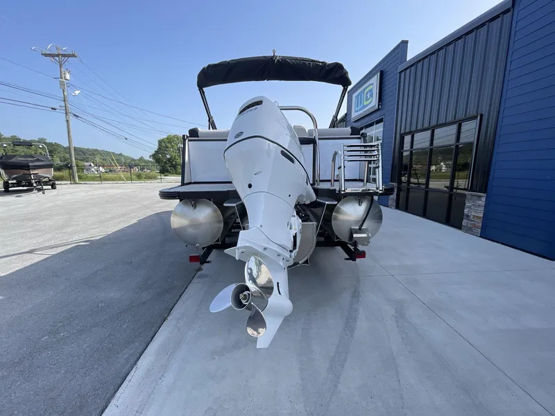 Slide: The Image of 2024 Tahoe Pontoon 23 Cascade Versatile Rear Lounger with outboard motor, parked outside dealership. - 7