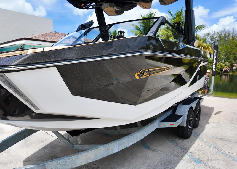 Slide: The Image of 2025 Nautique G23 boat on trailer, sleek design, black and white finish, sunny day. - 15