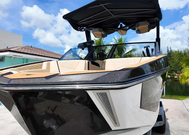 Slide: The Image of 2025 Nautique G23 boat with sleek design, parked outdoors under a clear blue sky. - 17