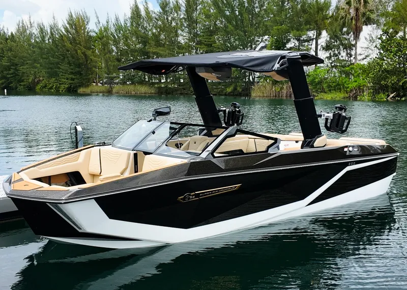 Slide: The Image of 2025 Nautique G23 boat on a serene lake with lush greenery. - 3